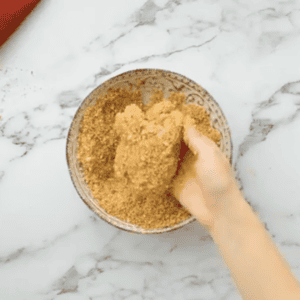 dipping a chicken thigh in seasoned breadcrumbs.