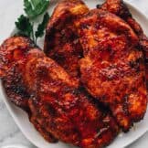 BBQ chicken breasts on a white plate after cooking