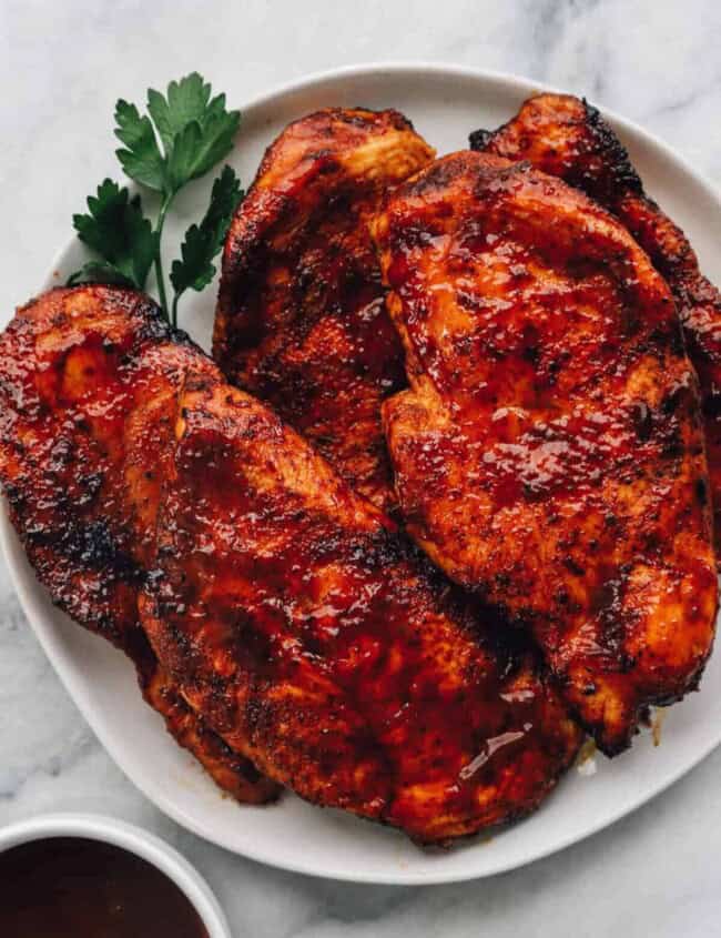 BBQ chicken breasts on a white plate after cooking