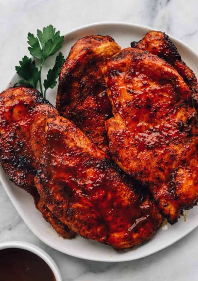BBQ chicken breasts on a white plate after cooking
