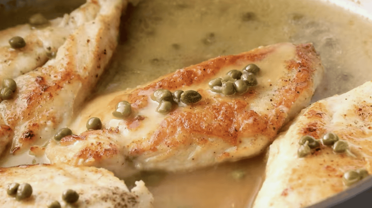Capers are placed on top of cooked chicken.