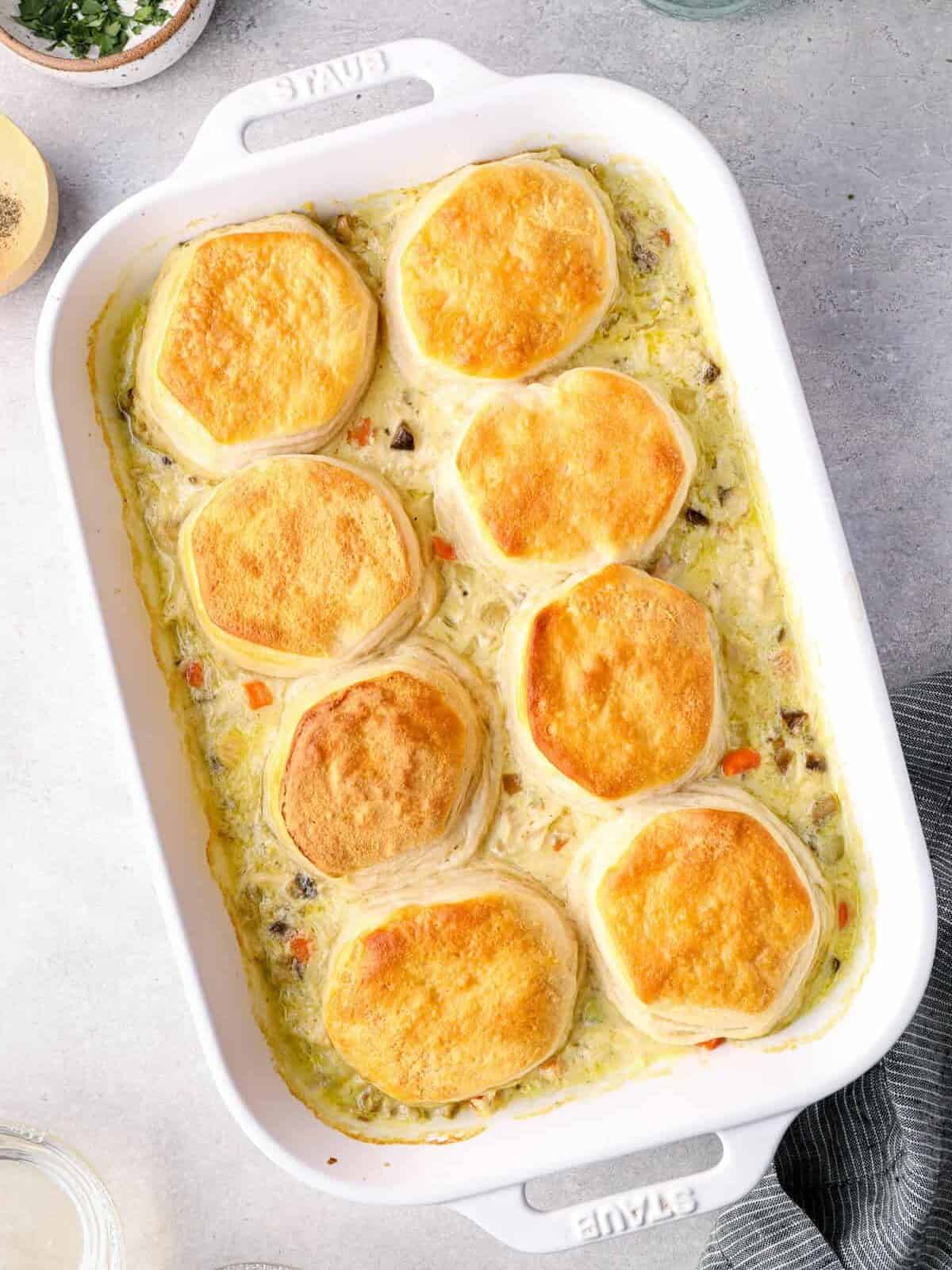 chicken pot pie casserole topped with biscuits in a white baking dish after baking