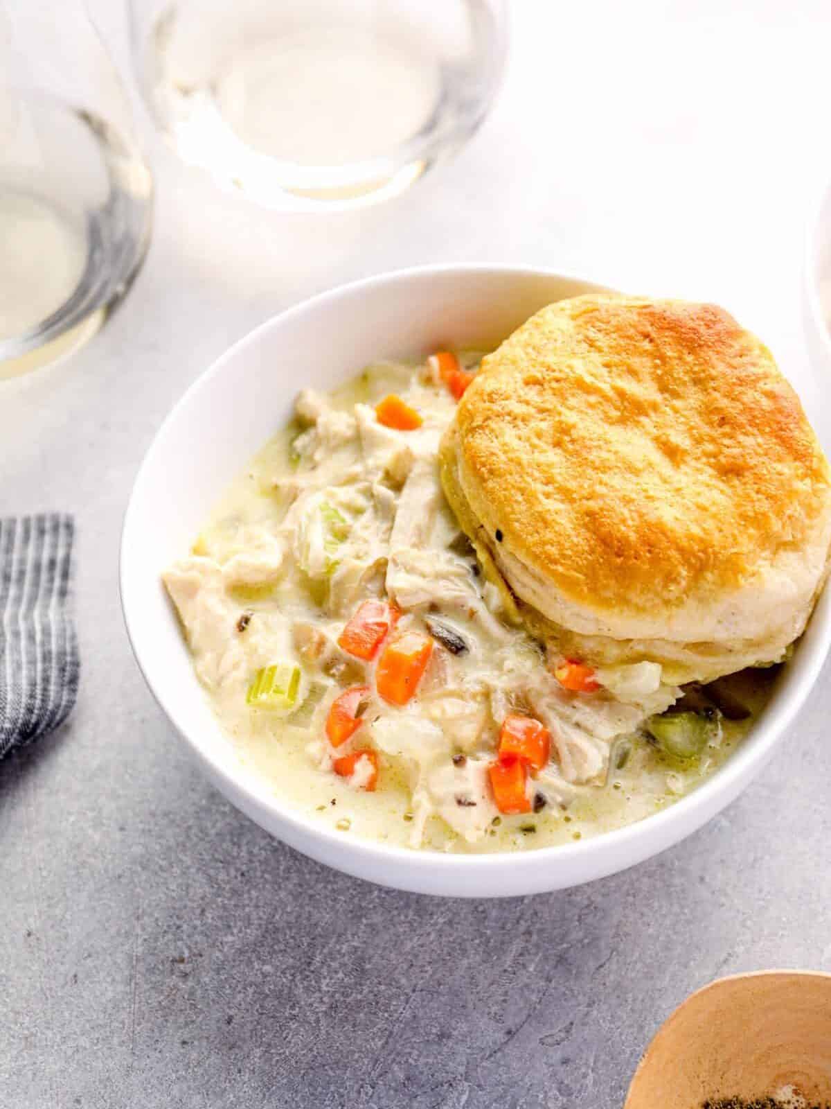 chicken pot pie casserole with a biscuit in a white bowl