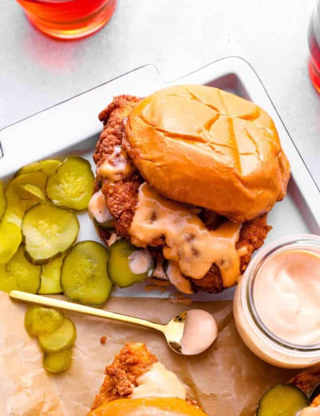 copycat Popeye's chicken sandwich on a tray with pickles and a jar of sauce