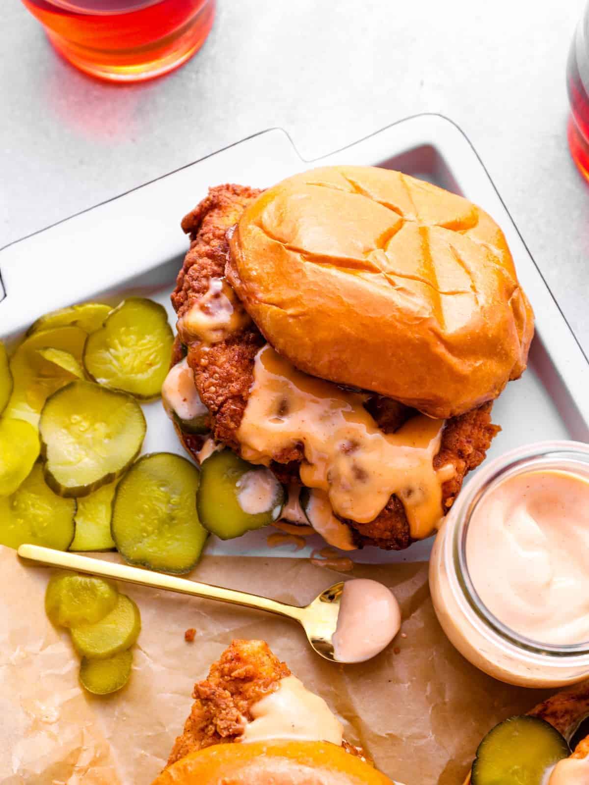 copycat Popeye's chicken sandwich on a tray with pickles and a jar of sauce