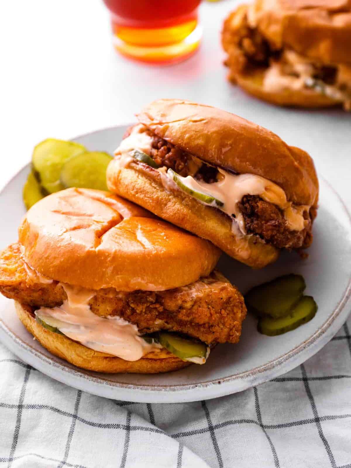 two Popeyes chicken sandwiches on a plate with pickles