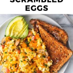 a plate of scrambled eggs with avocado and toast.