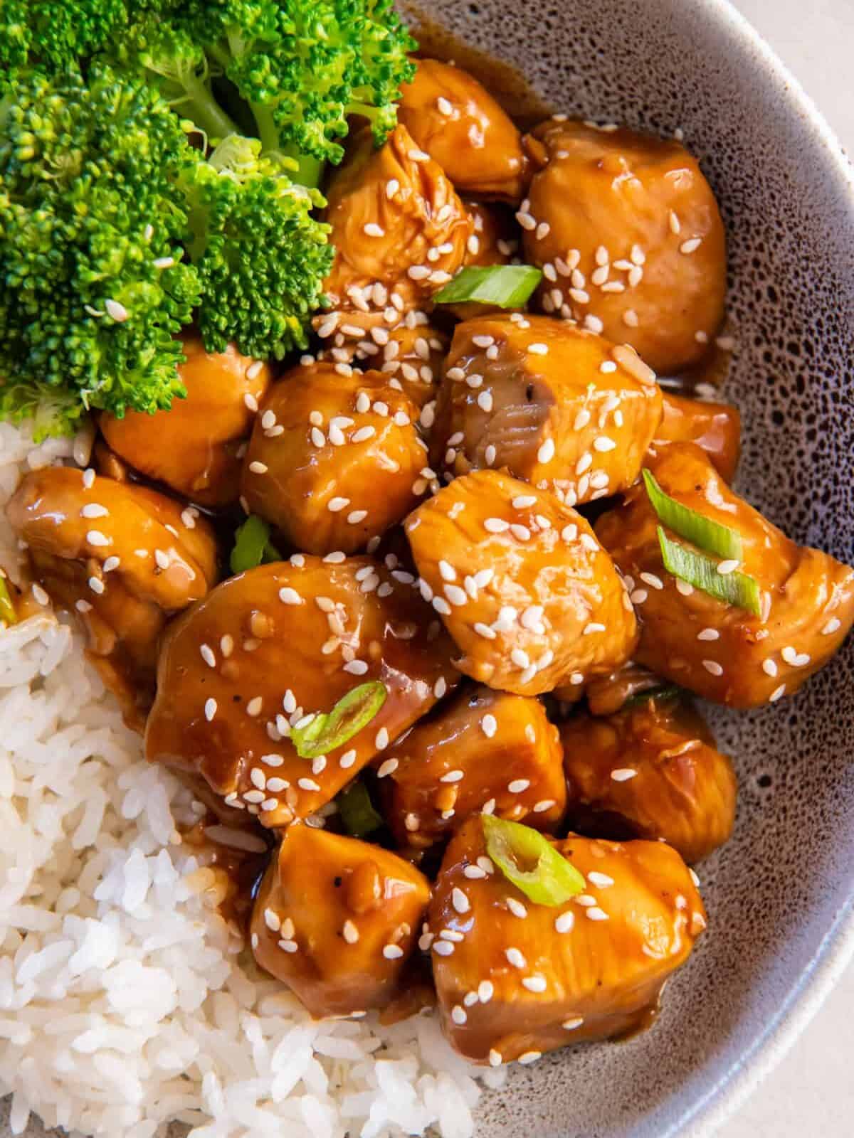 close up view of mandarin chicken in a gray bowl with rice and broccoli.