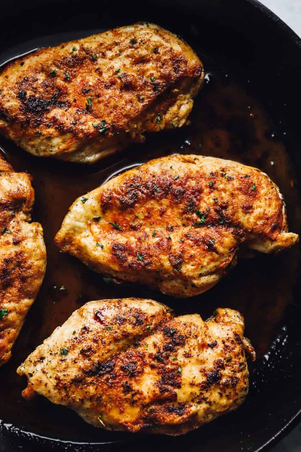 chicken breasts searing in a cast iron skillet