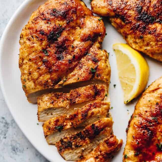 pan seared chicken breasts on a plate, partially sliced