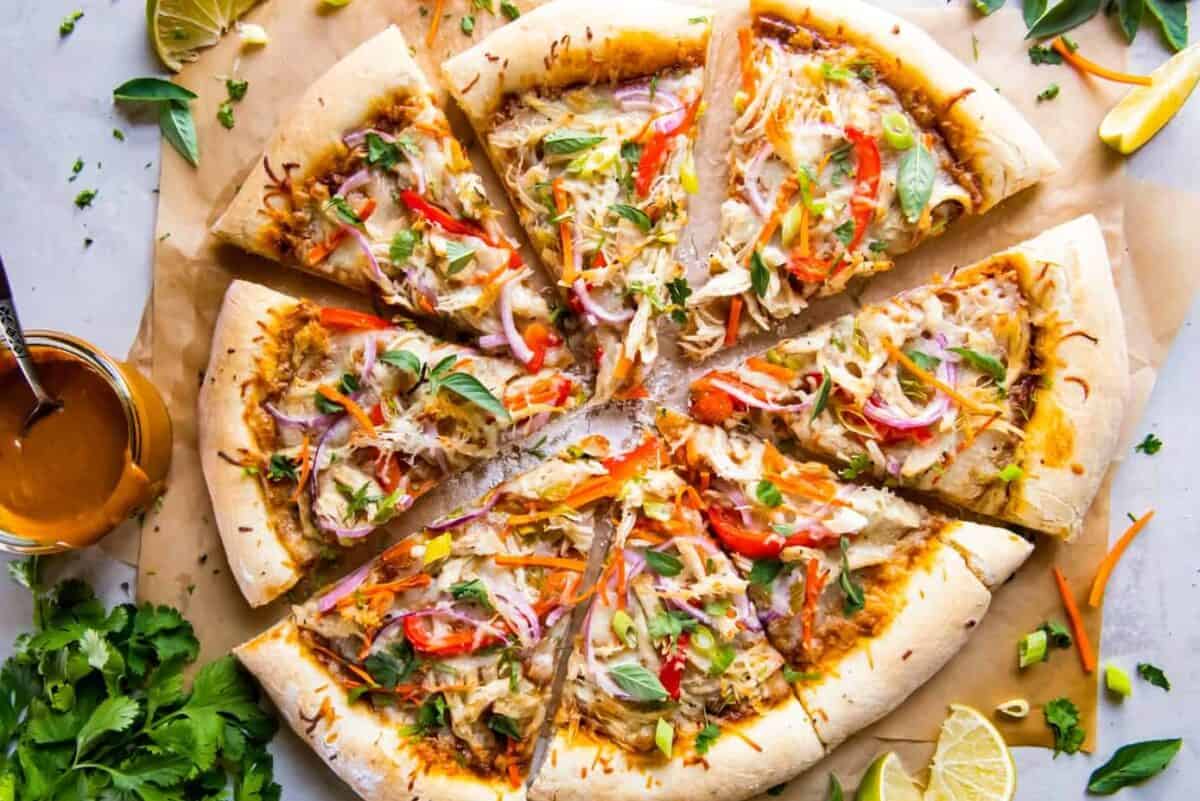 overhead view of a thai chicken pizza cut into slices