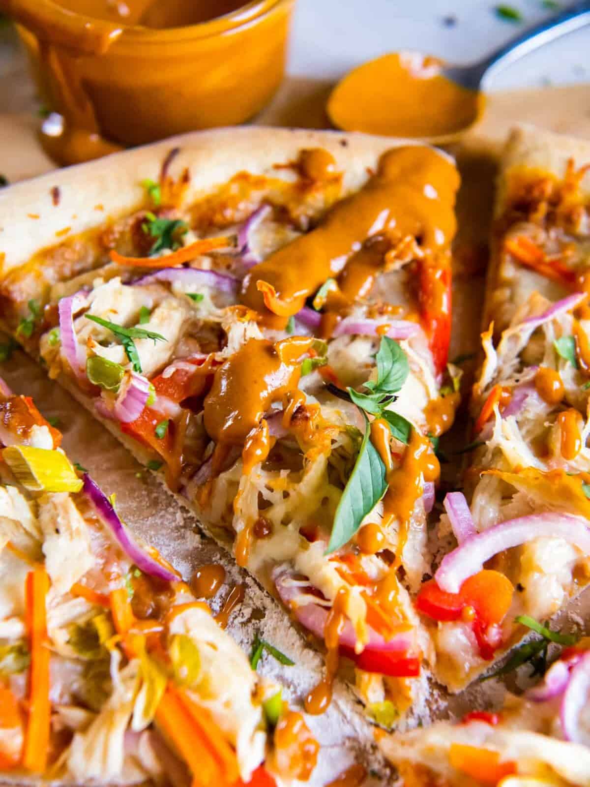 close up on slices of pizza drizzled in peanut sauce