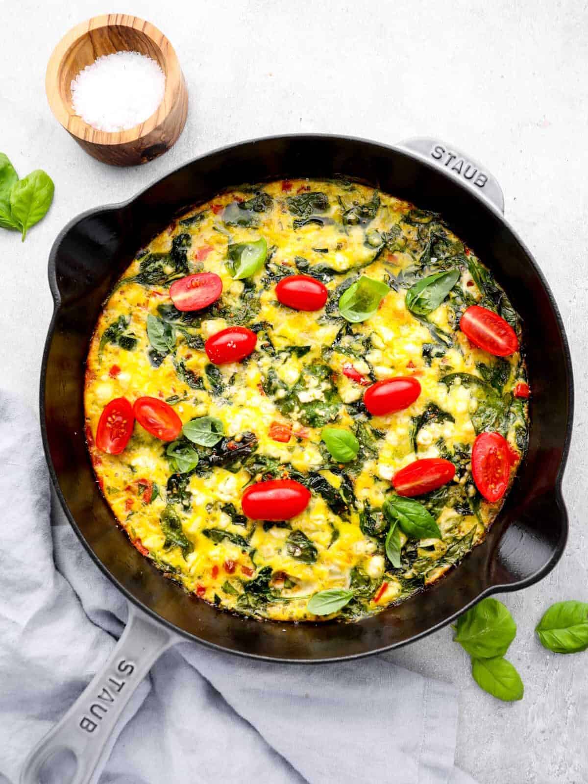 overhead view of a vegetable frittata with spinach and tomatoes