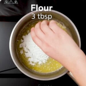 pouring flour over melted butter in a saucepan overlaid with text "flour 3 tbsp".
