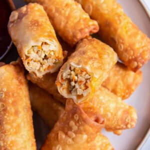 close up on a plate of egg rolls, one is cut in half to show the filling