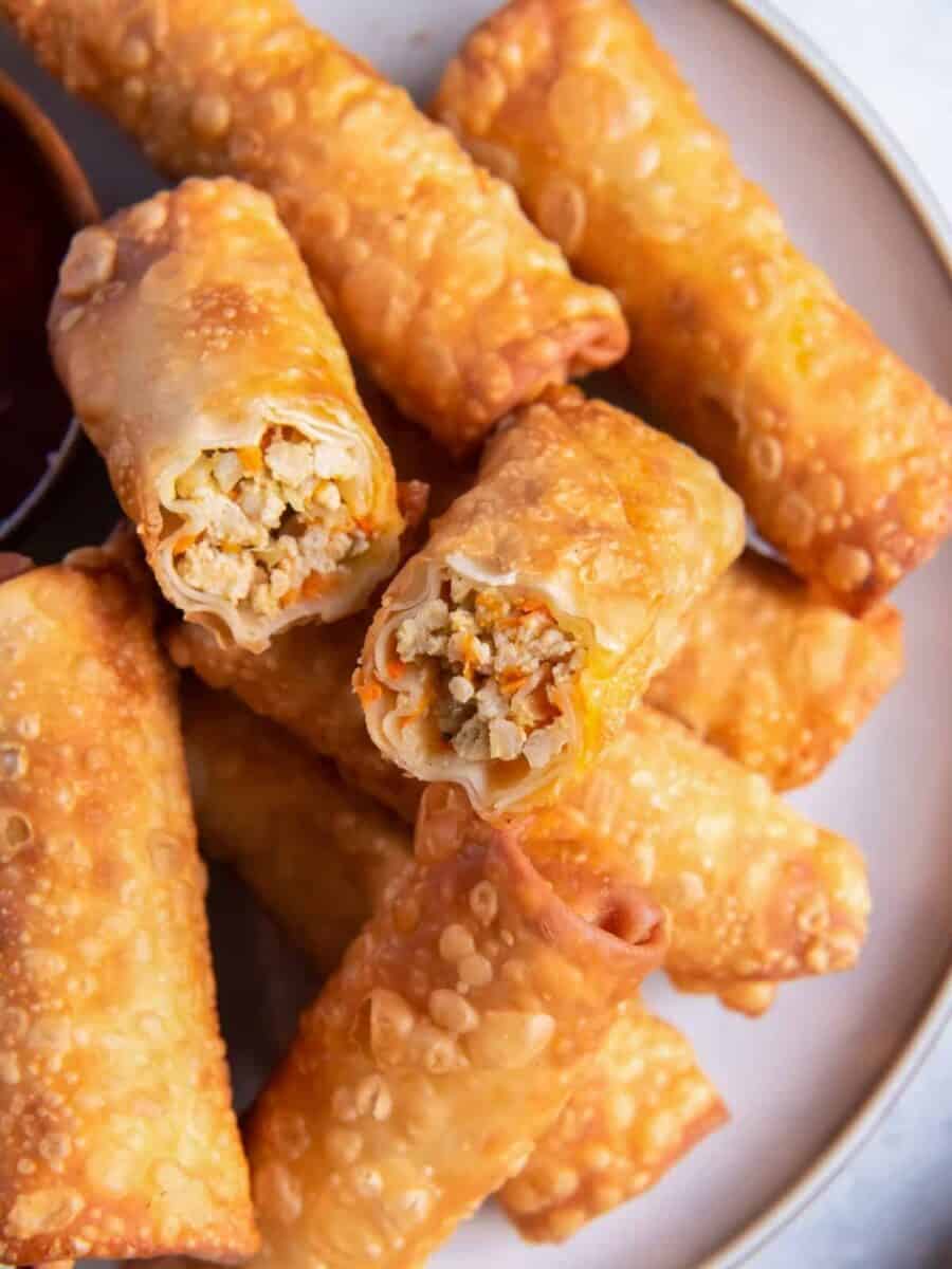 close up on a plate of egg rolls, one is cut in half to show the filling