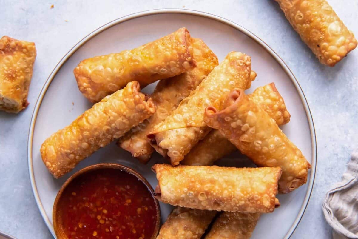 A plate of chicken egg rolls with dipping sauce.