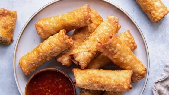 a plate of chicken egg rolls with dipping sauce