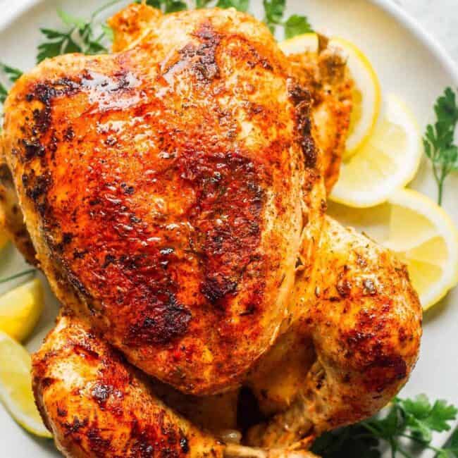 seasoned whole chicken with lemon on white plate