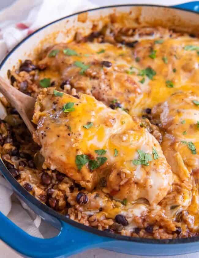 cheesy chicken breasts with rice and beans in a skillet