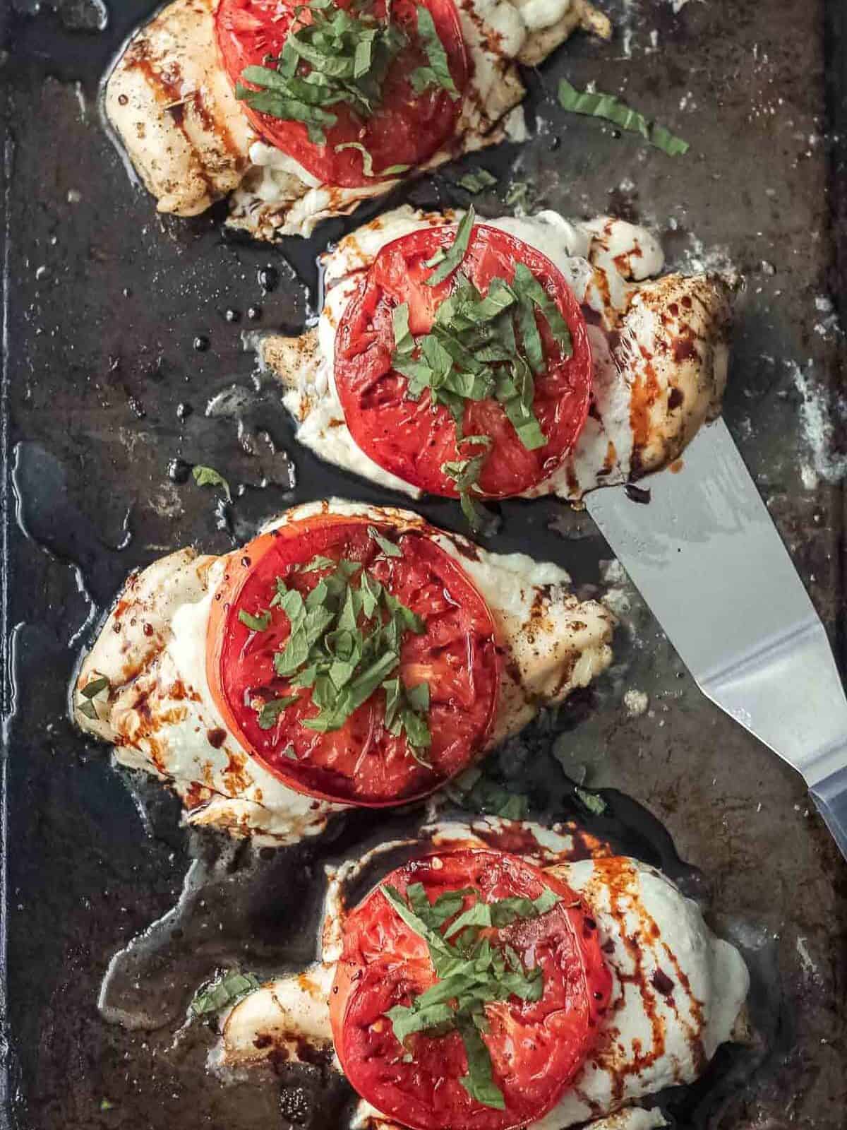 overhead view of 3 caprese chicken breasts on a sheet pan