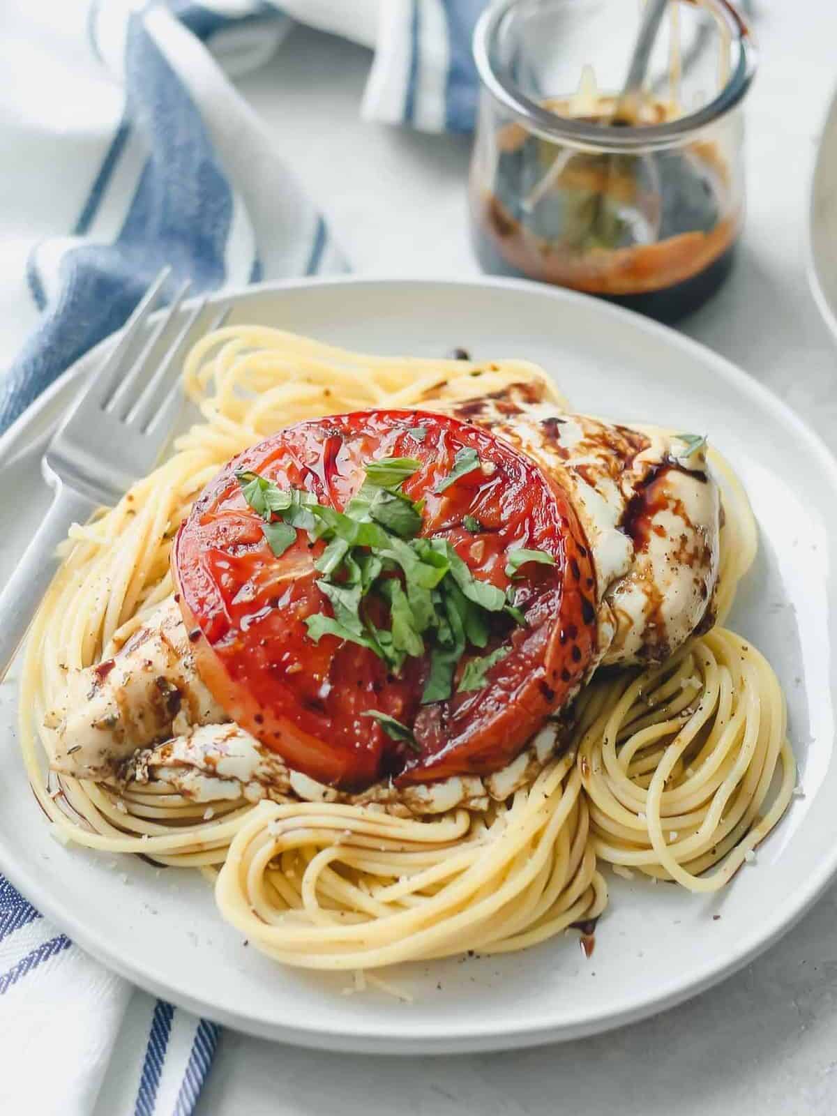 chicken breasts topped with mozzarella and tomatoes on a bed of spaghetti.