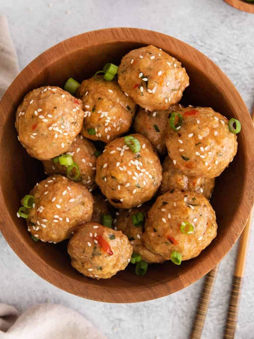 asian meatballs in a wooden bowl with sesame seeds.