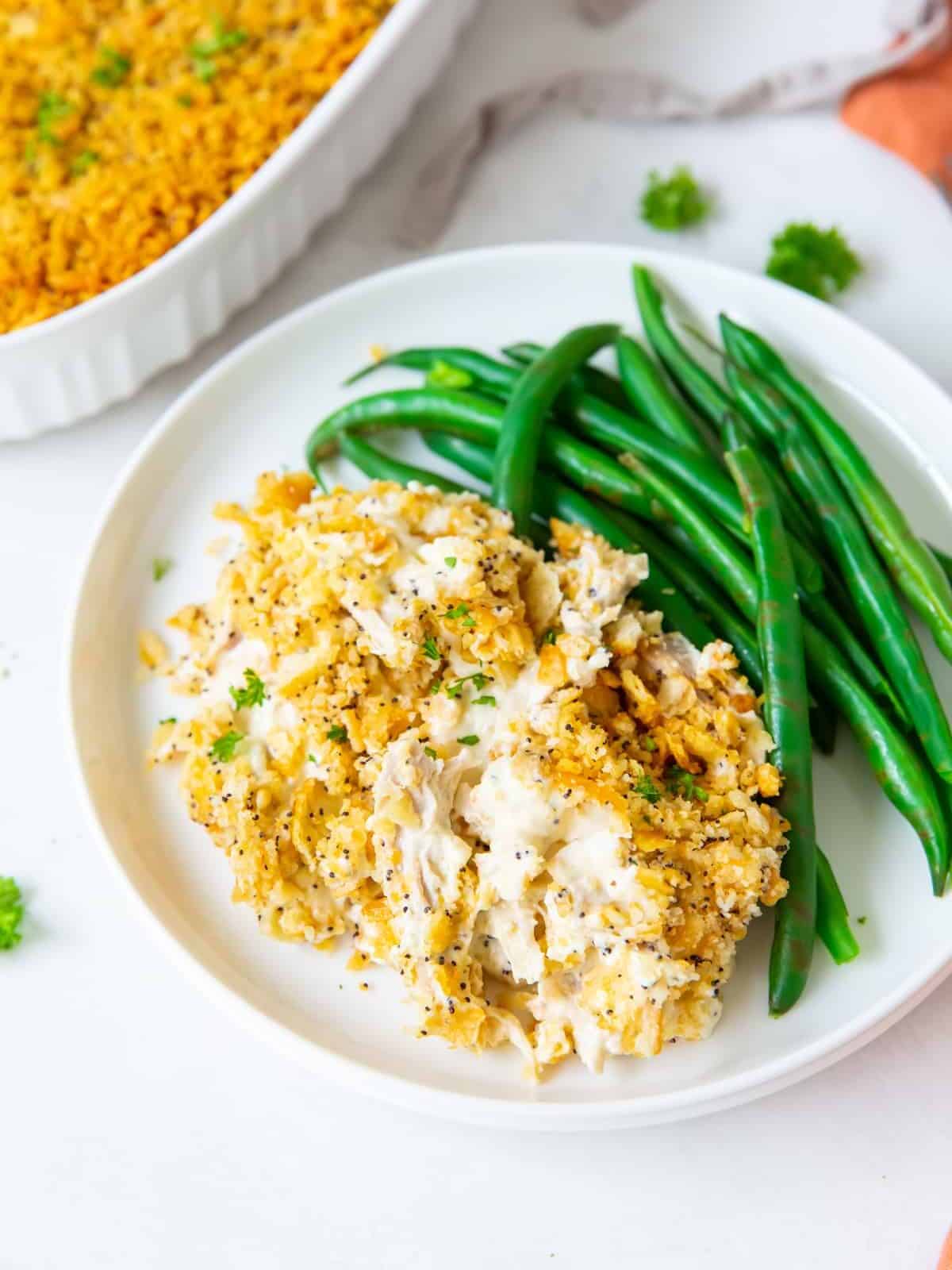 a white plate filled with poppyseed chicken and green beans