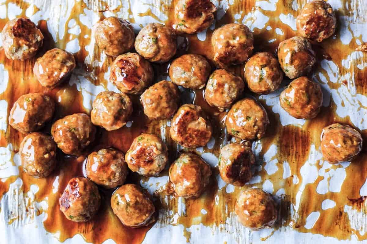 Chicken meatballs on parchment covered in the Asian sauce