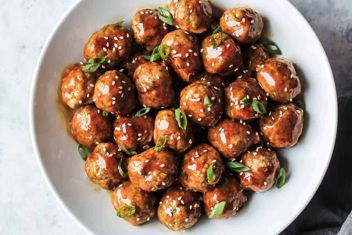Asian chicken meatballs in a white bowl garnished with green onion