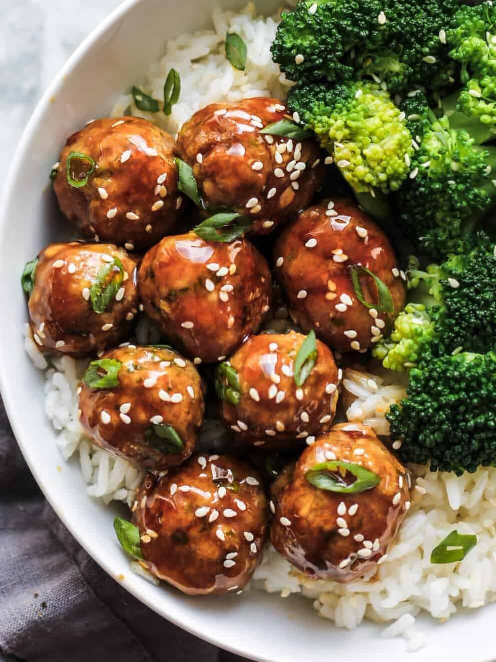 Meatballs on top of white rice and garnished