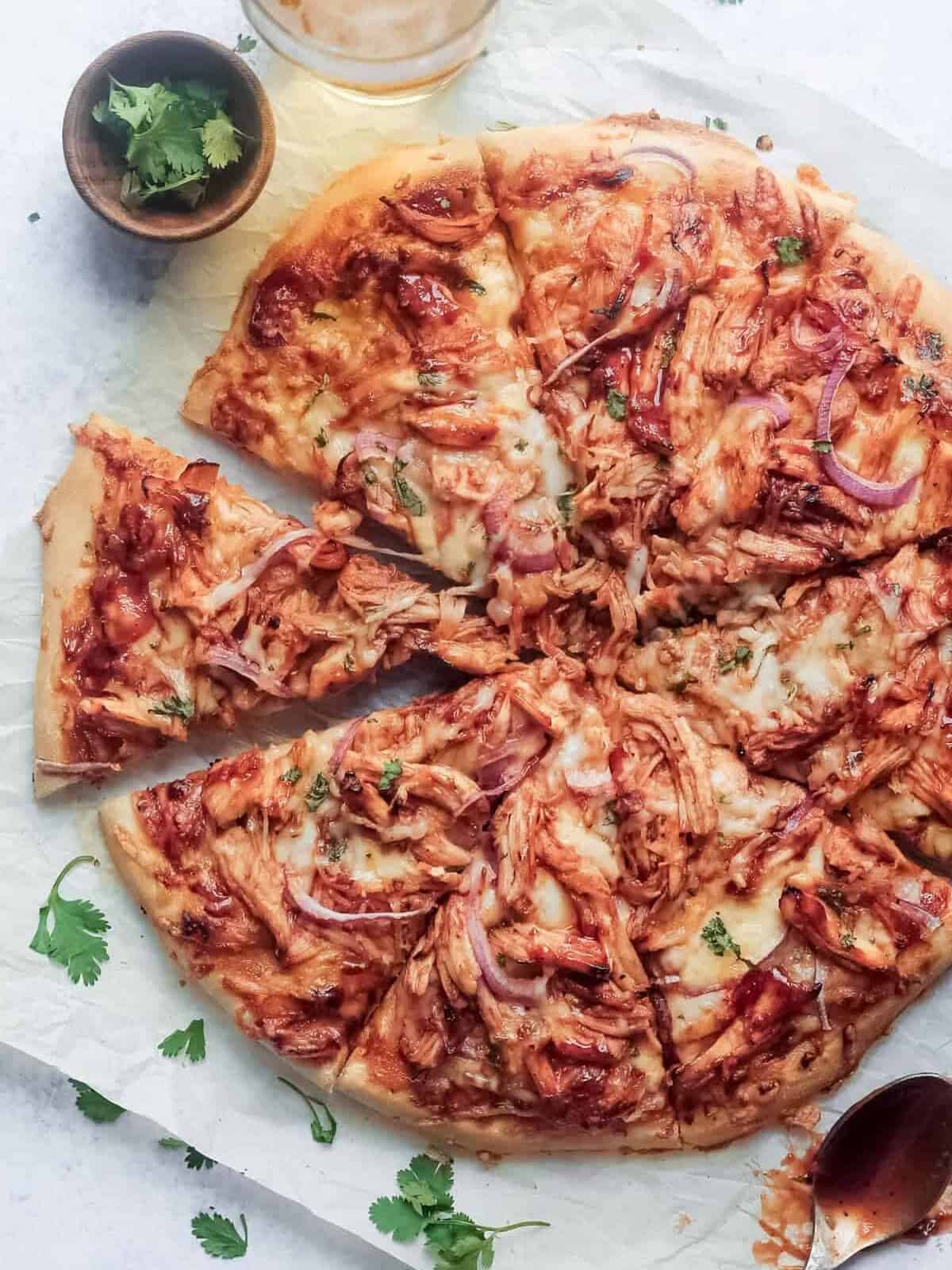 overhead view of a bbq chicken pizza topped with shredded chicken, red onions, and barbecue sauce