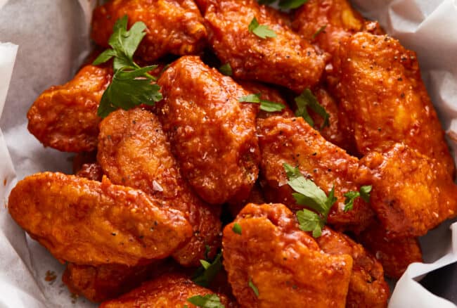 Chicken wings in a paper basket on a wooden table.