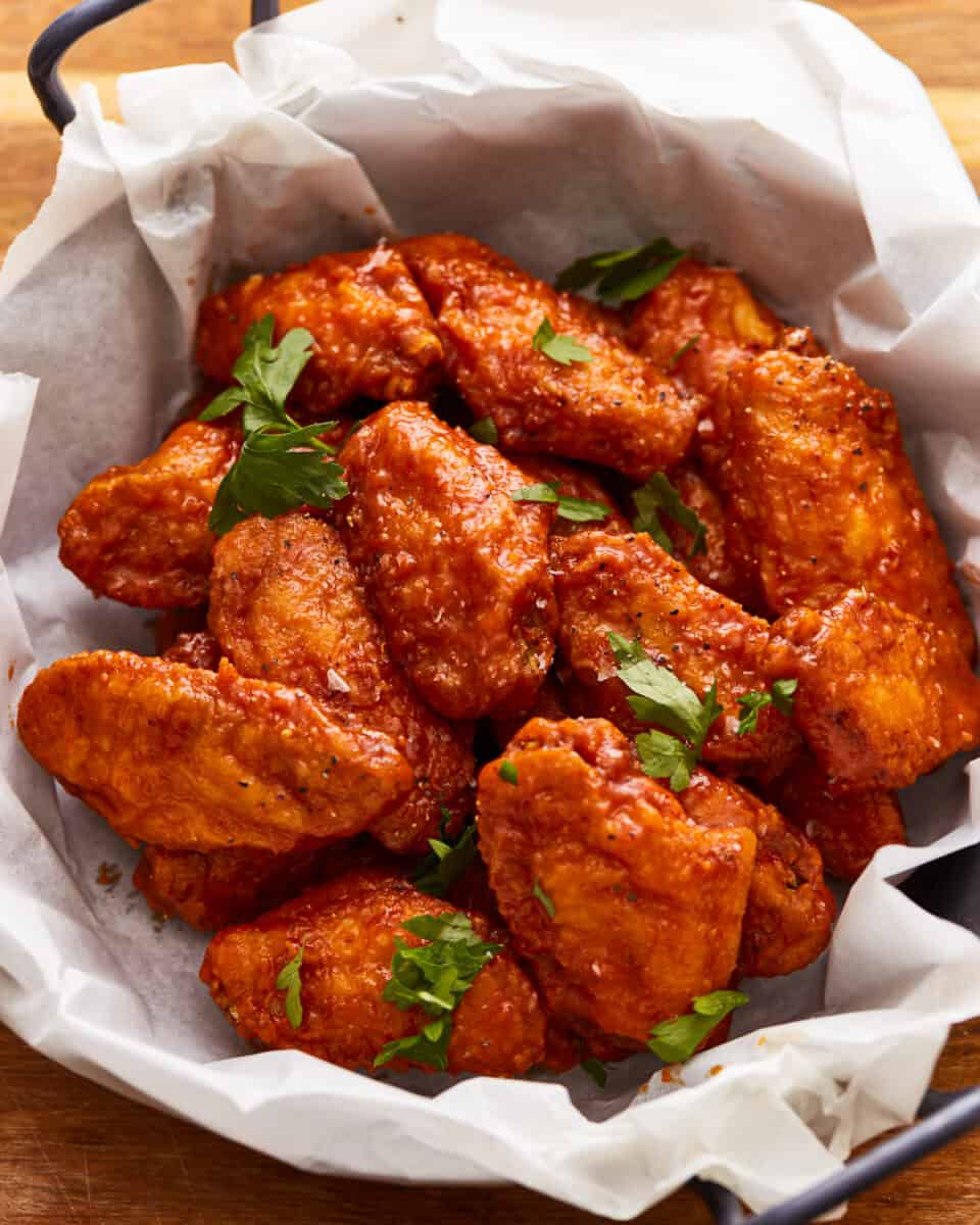 Chicken wings in a paper basket on a wooden table.