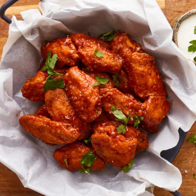 Bbq chicken wings in a bowl on a wooden table.