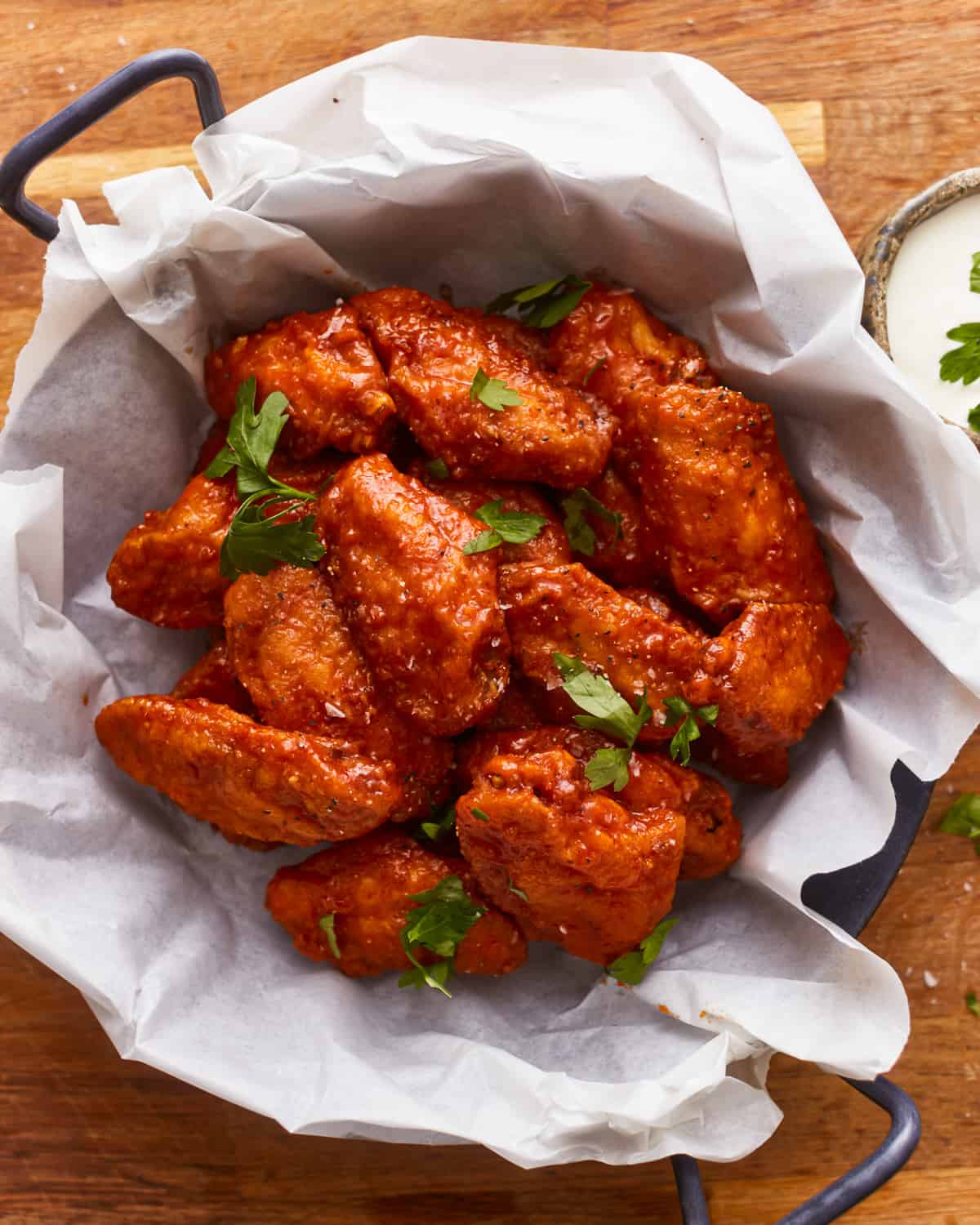 Bbq chicken wings in a bowl on a wooden table.