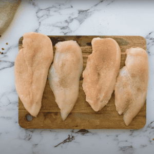 seasoned butterflied chicken breasts on a cutting board.