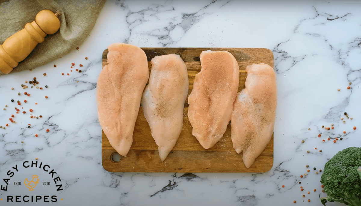 seasoned butterflied chicken breasts on a cutting board.