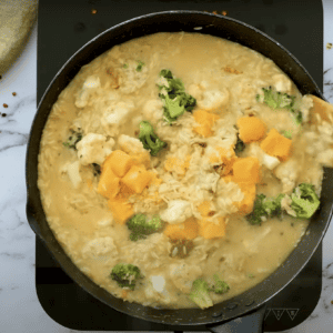 stirring cubed velveeta cheese into rice, broccoli, and cauliflower in a saucy skillet.