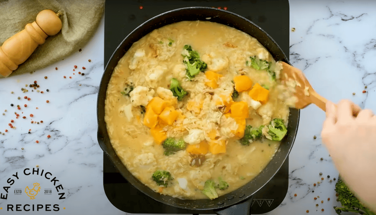 stirring cubed velveeta cheese into rice, broccoli, and cauliflower in a saucy skillet.