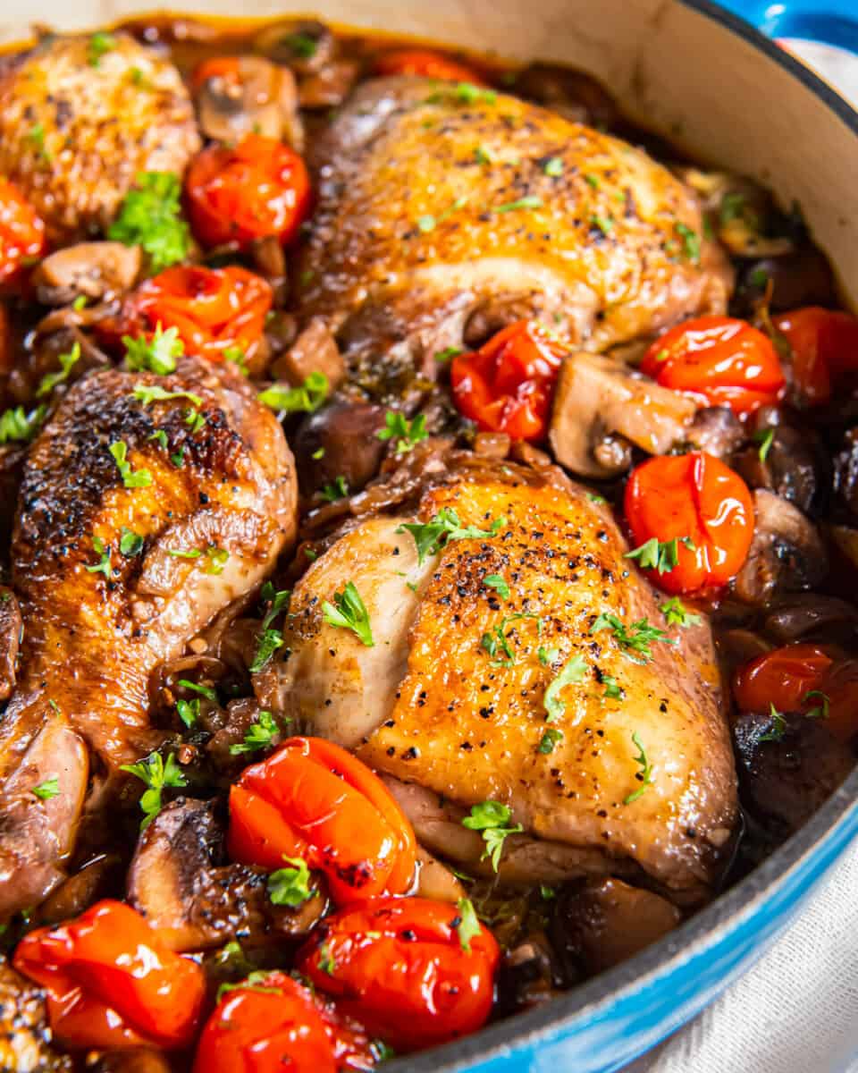 Roasted chicken with mushrooms and tomatoes in a pan.