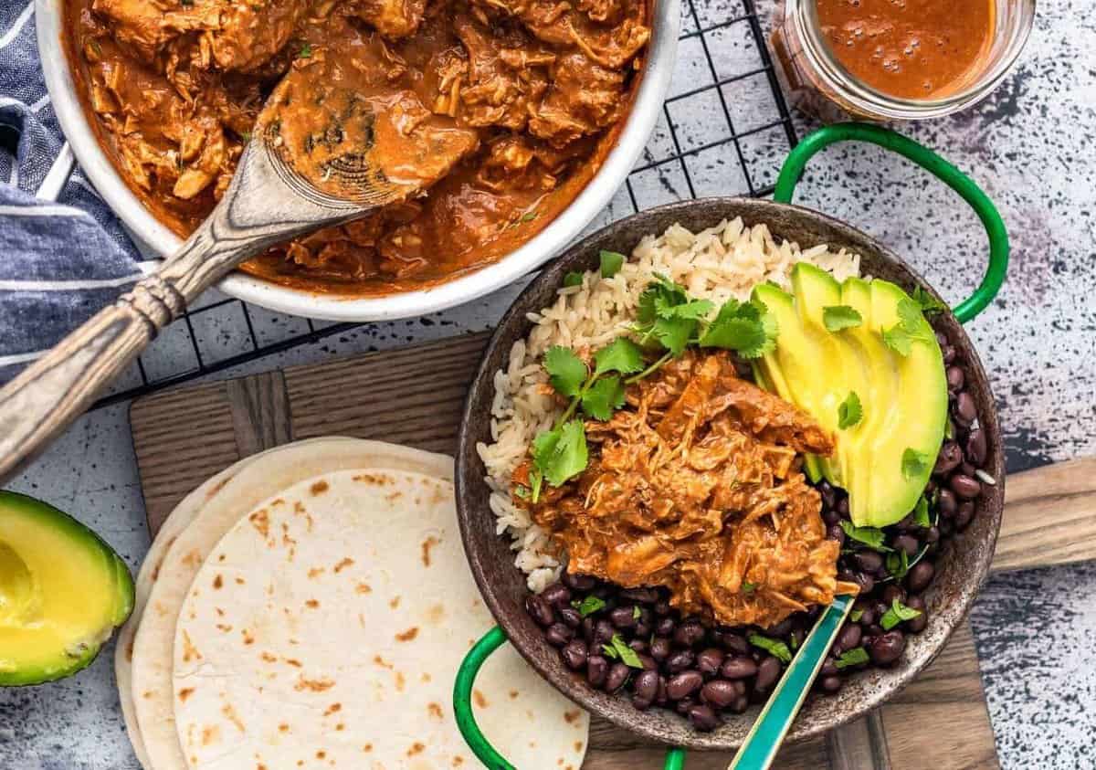 overhead picture of chicken mole in skillet plus plated with rice and black beans