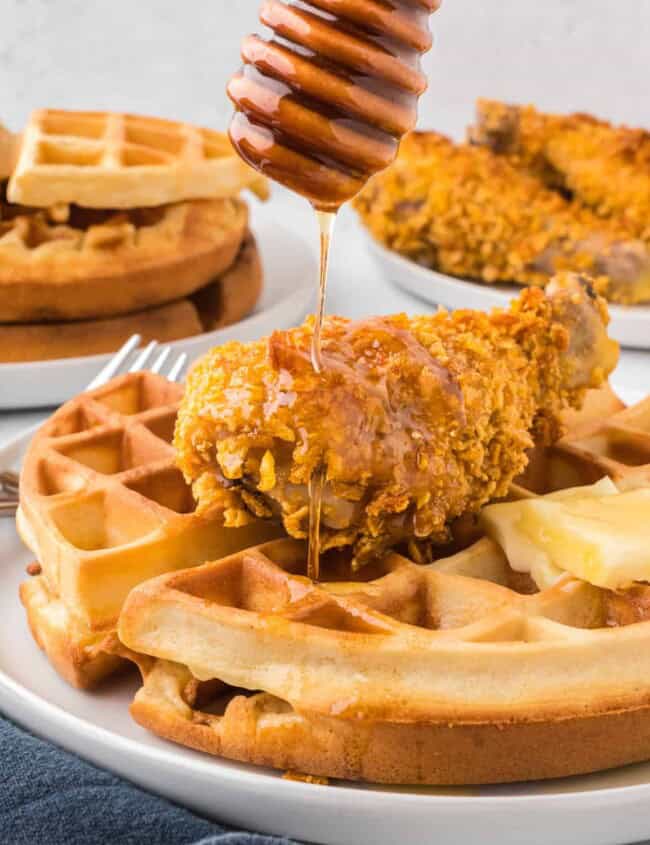 Waffles with chicken and honey drizzled on them.