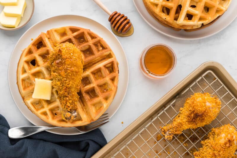 Waffles with chicken and honey on a tray.