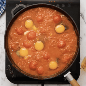 Simple chicken shakshuka recipe with tomatoes and eggs cooked in a pan.