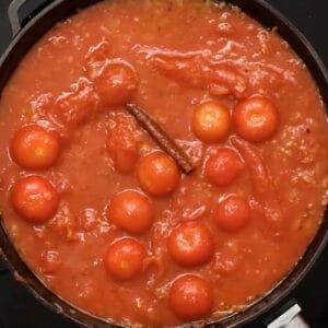 cherry tomatoes, cinnamon, and cumin simmering with whole peeled tomatoes, onion, and garlic.