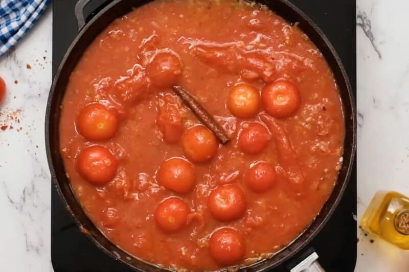 cherry tomatoes, cinnamon, and cumin simmering with whole peeled tomatoes, onion, and garlic.
