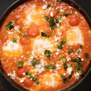 overhead view of eggs in purgatory topped with goat cheese and cilantro.
