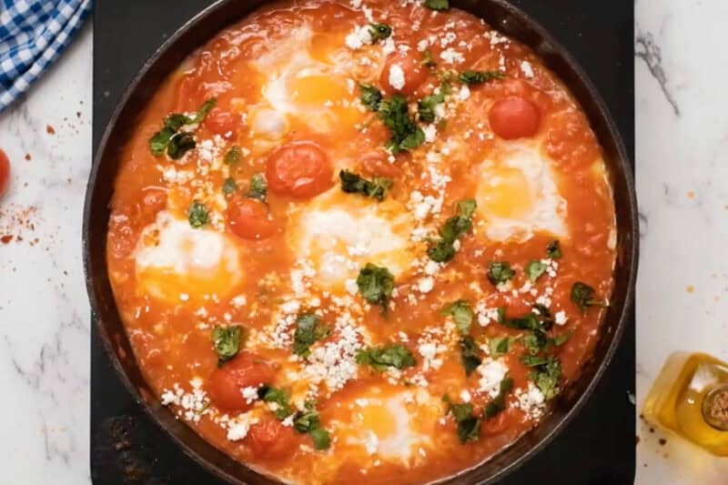 overhead view of eggs in purgatory topped with goat cheese and cilantro.
