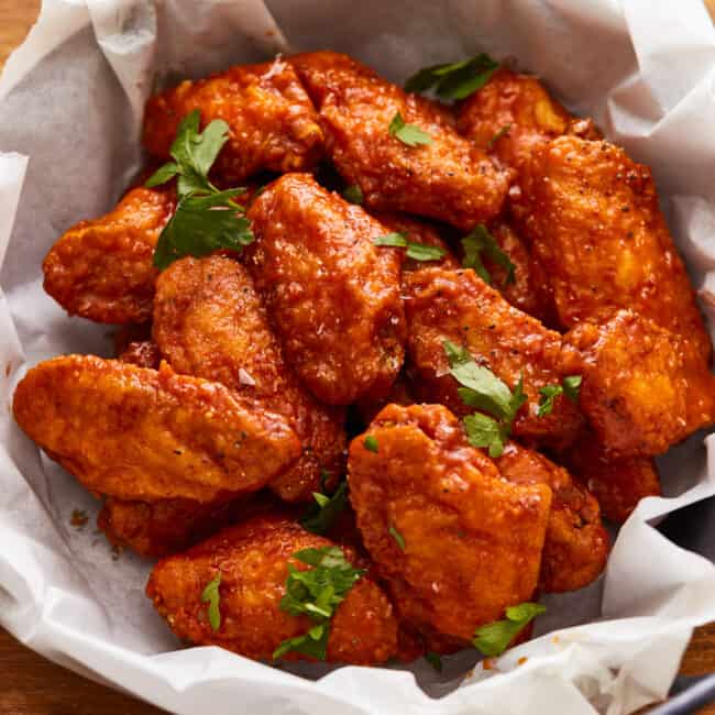 Chicken wings in a bowl on a wooden table.